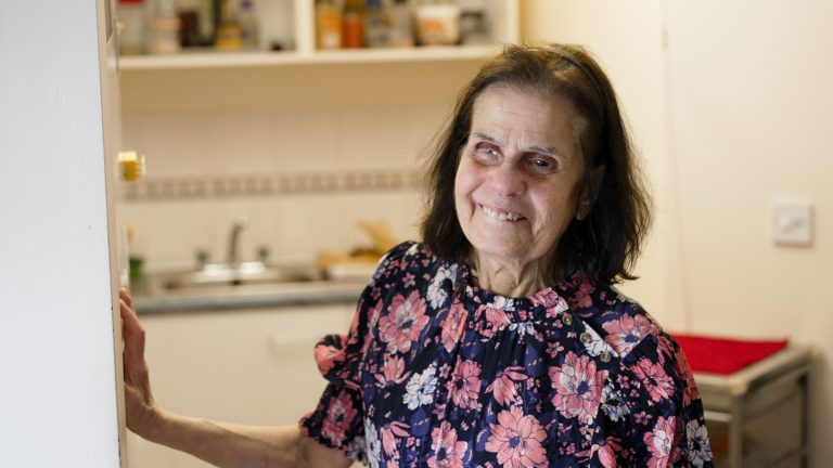 A woman stands and smiles to camera